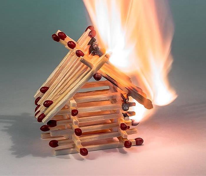 Match sticks fashioned in the shape of a house lit on fire